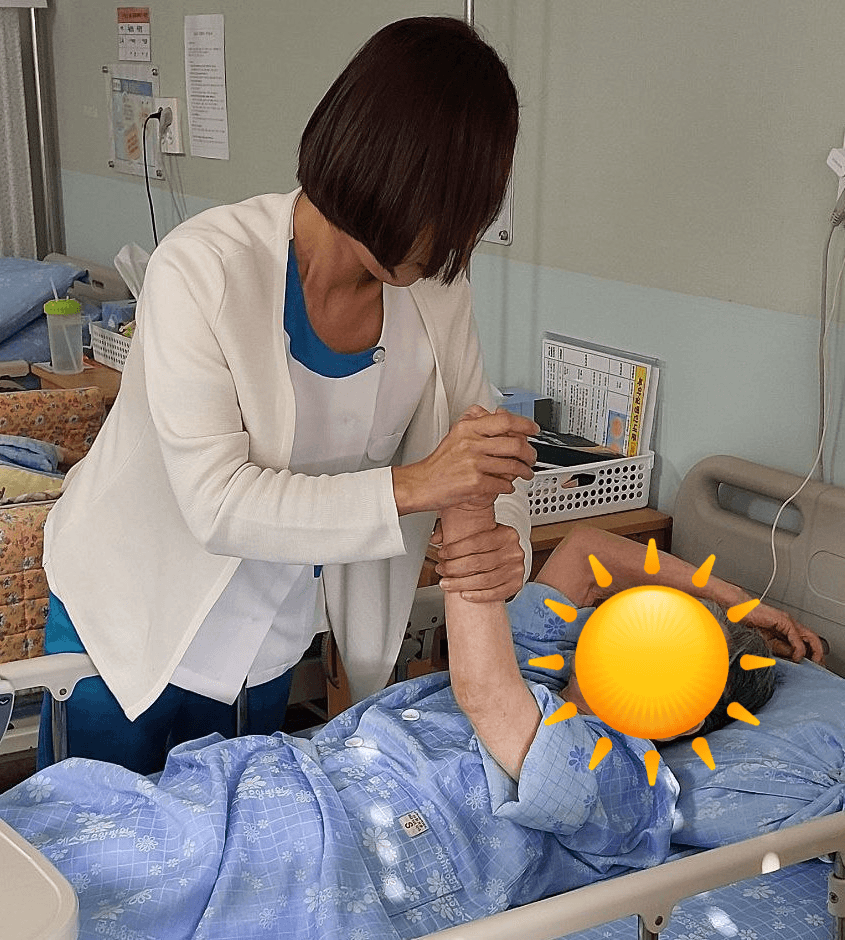 광주 에스웰 요양병원 환자안전실장이 치매 어르신과 손잡고 마주 바라보며 심리적 안정을 돕는 모습